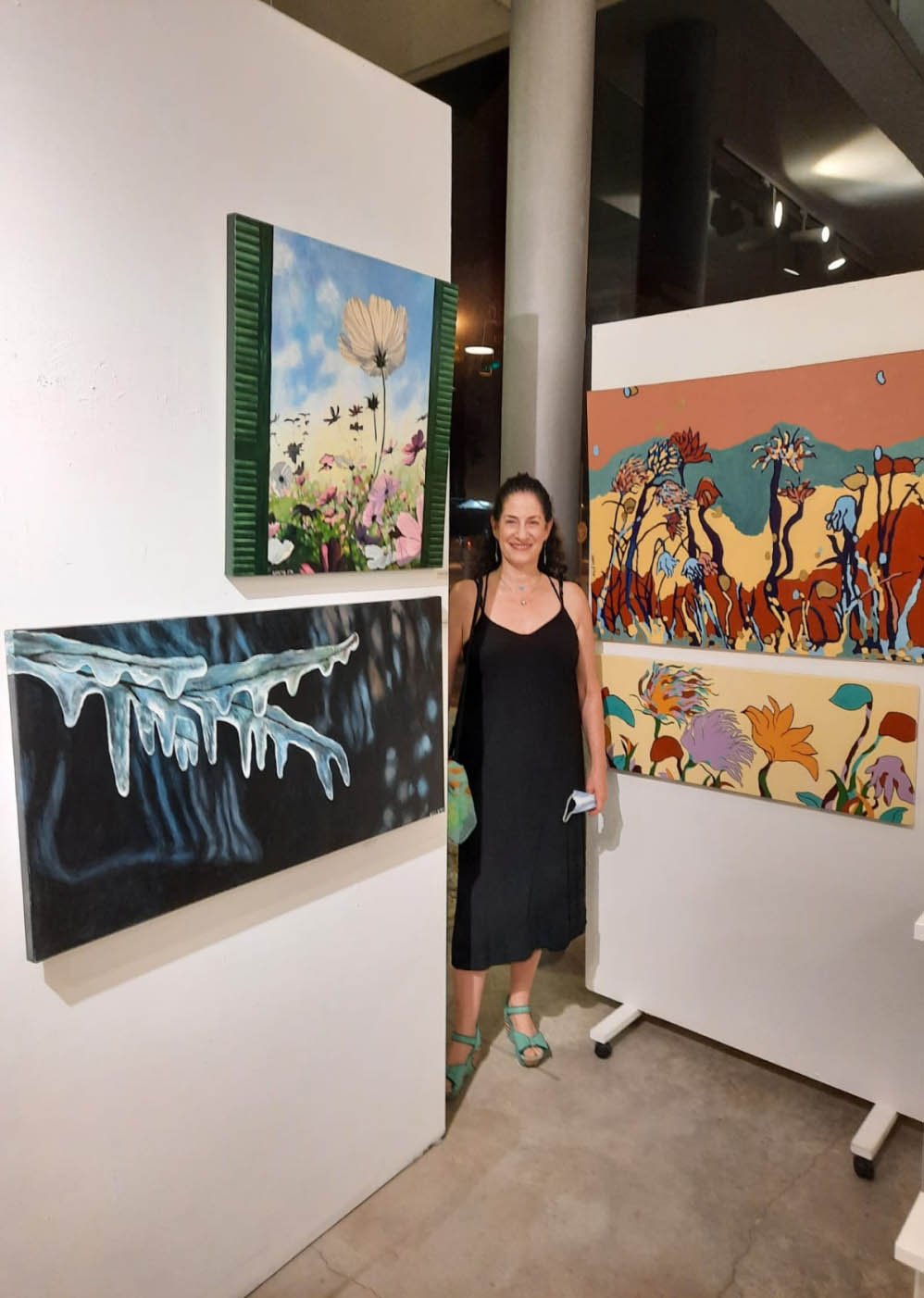 Sharon standing beside her paintings at an art exhibition